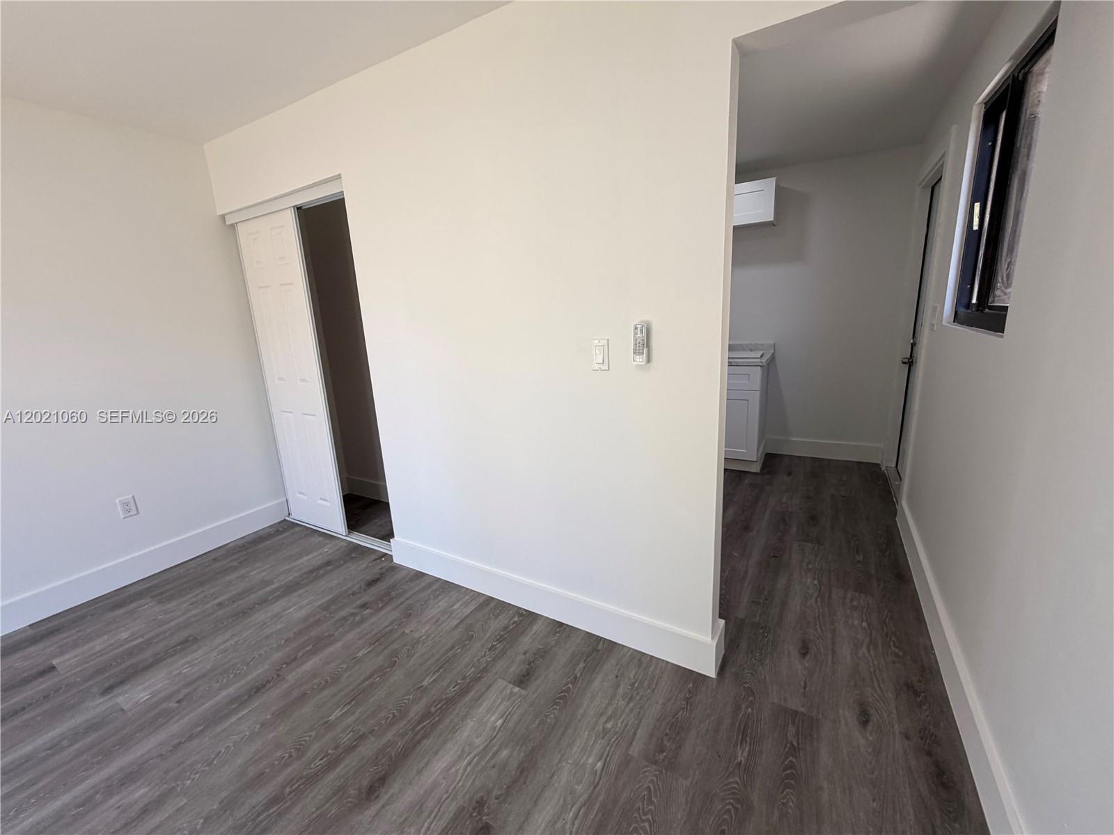A room with gray wood-look flooring, white walls, a closet, and an adjacent kitchenette area — 16536 SW 54th St # 1, Miami FL 33185, MIAMI, FL