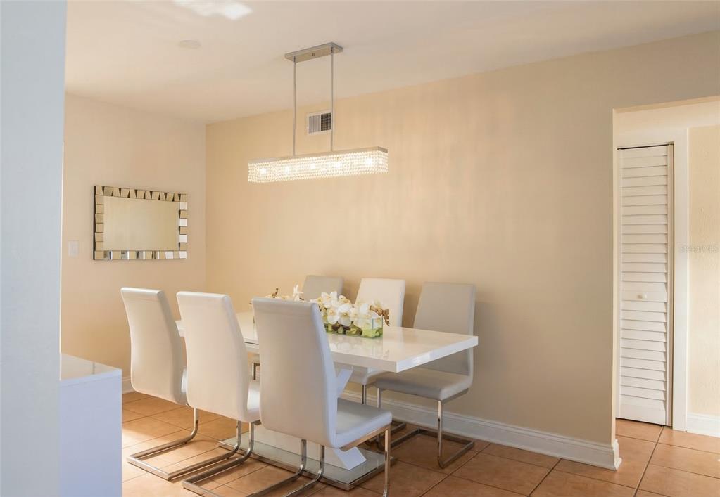 A dining room features a white table, six modern chairs, and a rectangular crystal chandelier — 7327 ABONADO ROAD UNIT 7327, TAMPA, FL