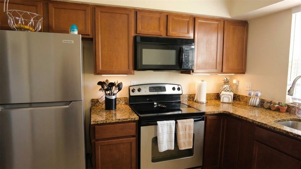 A kitchen features wood cabinets, granite countertops, and stainless steel appliances — 7327 ABONADO ROAD UNIT 7327, TAMPA, FL
