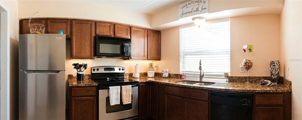A kitchen features dark wood cabinets, stainless steel appliances, and granite countertops — 7327 ABONADO ROAD UNIT 7327, TAMPA, FL