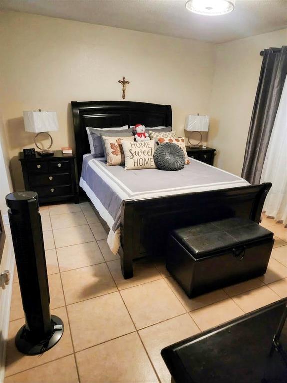 A bedroom features a dark wood bed frame, two nightstands, and a black storage bench — 7327 ABONADO ROAD UNIT 7327, TAMPA, FL