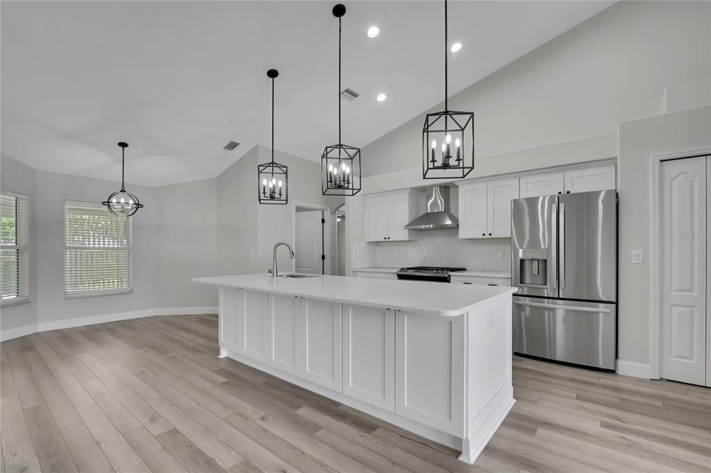 A kitchen featuring a white island, stainless steel appliances, and pendant lighting over wood floors — 6164 N SILVER PALM WAY, BEVERLY HILLS, FL