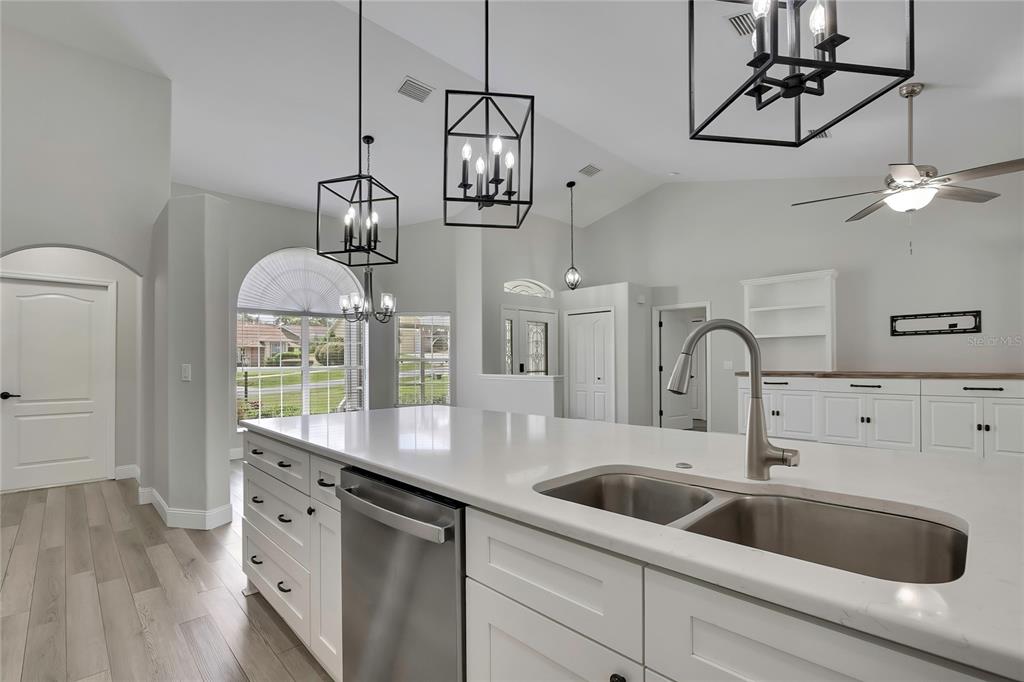A modern kitchen features a large white island, stainless steel sink, and black lantern pendant lights — 6164 N SILVER PALM WAY, BEVERLY HILLS, FL