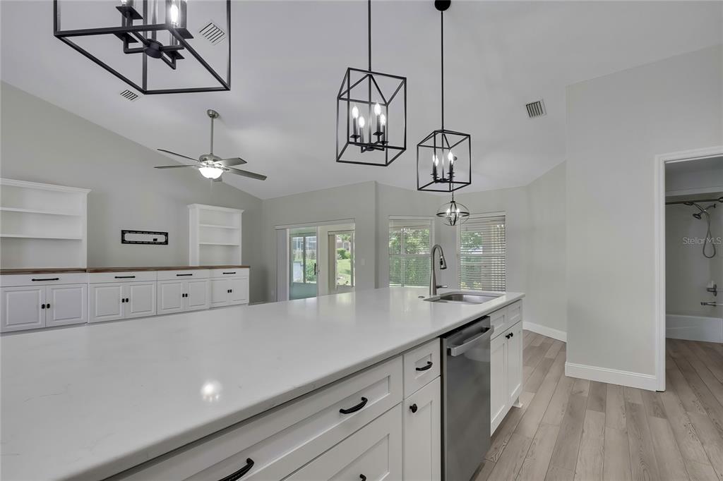 A kitchen island with a white countertop sits in front of white cabinets and lighting — 6164 N SILVER PALM WAY, BEVERLY HILLS, FL