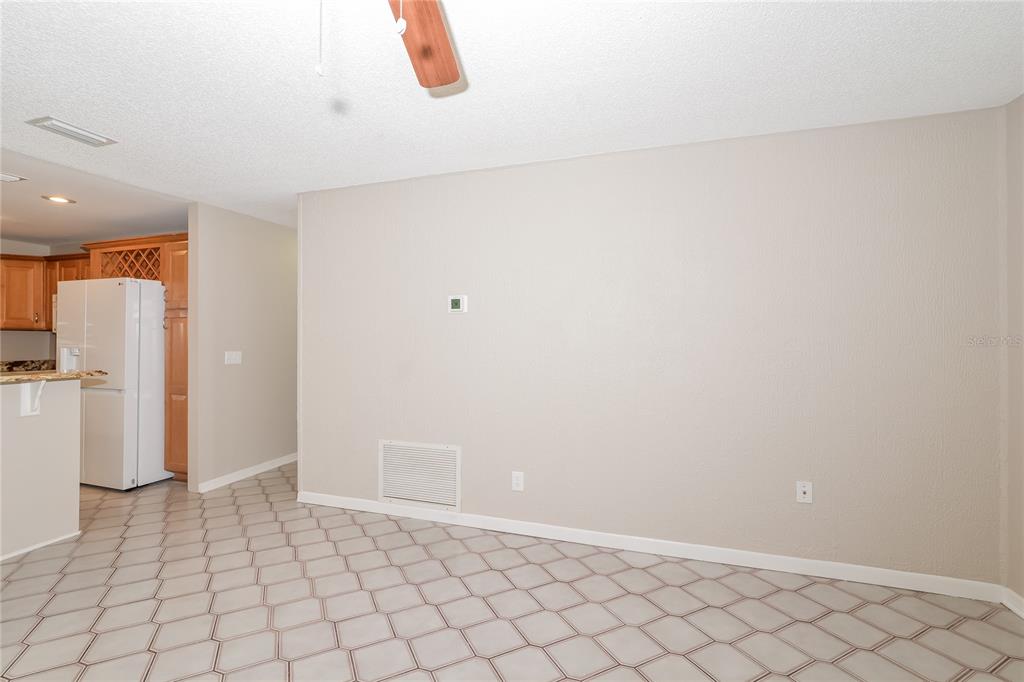 A room with beige walls, a white tile floor, and a view into a kitchen — 8873 ASPEN AVENUE, ORLANDO, FL