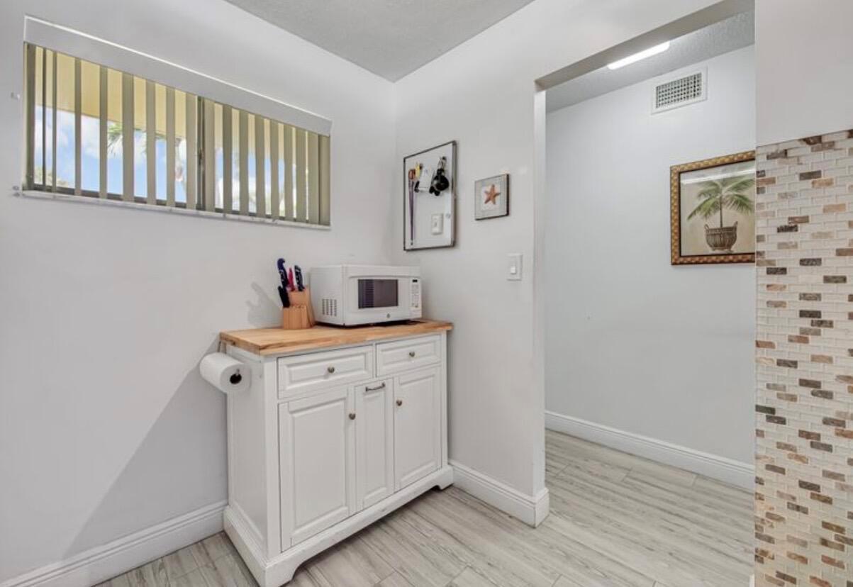 A white cabinet with a wooden top and microwave sits against a wall with blinds — 2855 Garden Drive S # 102, FL 33461, FL