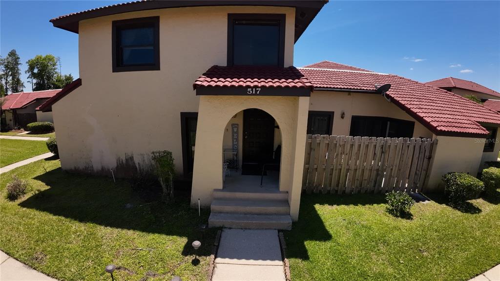 A two-story house with a tan stucco exterior, red tile roof, and arched entryway — 517 HUNTER CIRCLE, KISSIMMEE, FL