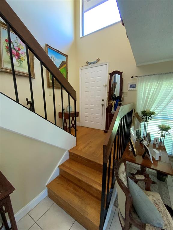 An entryway features a wooden staircase with black railings, a white front door, and hardwood floors — 517 HUNTER CIRCLE, KISSIMMEE, FL