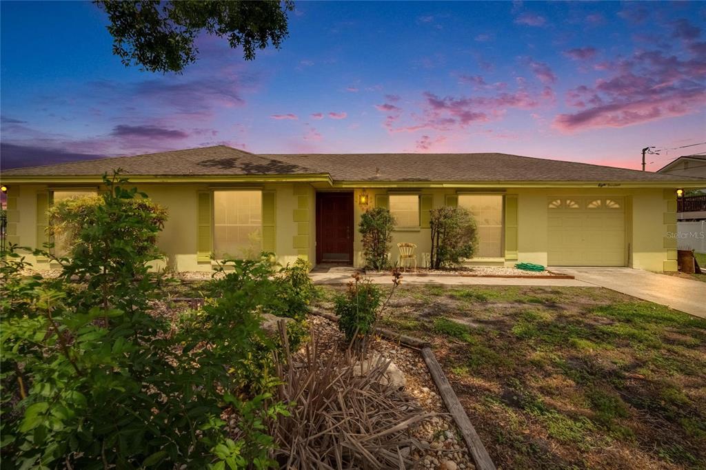 A single-story house with a yellow exterior, a front-facing garage, and a landscaped yard — 814 SEABREEZE DRIVE, RUSKIN, FL