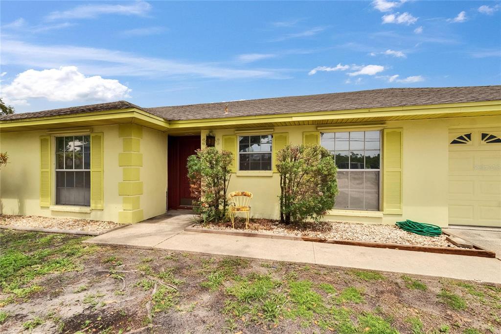 A single-story house with yellow stucco walls, a brown roof, and a concrete walkway — 814 SEABREEZE DRIVE, RUSKIN, FL