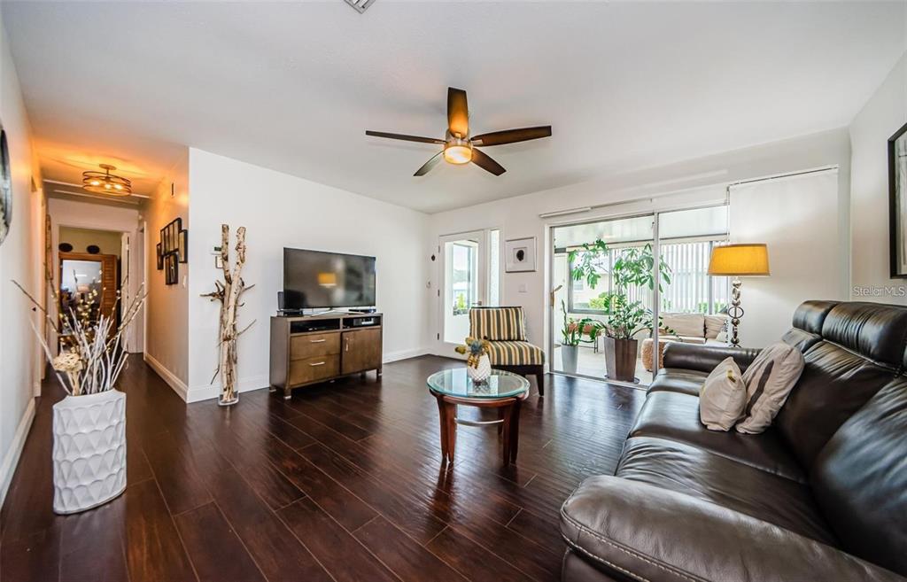 A living room with dark wood floors, a leather sofa, and a glass-topped coffee table — 2739 SHERBROOKE LANE UNIT B, PALM HARBOR, FL