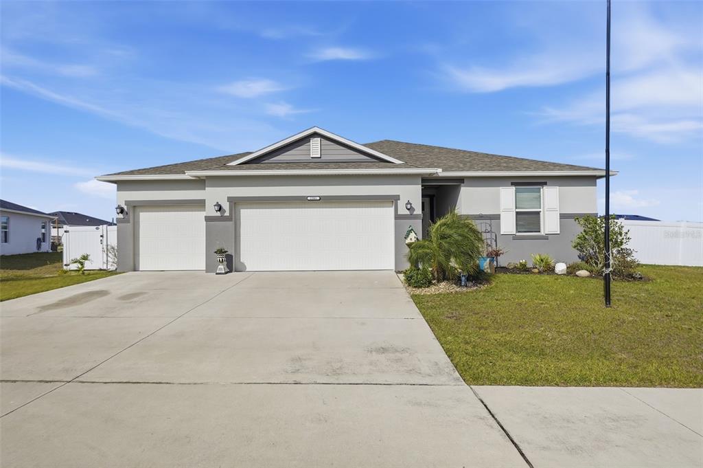 A single-story house with a two-car garage, gray exterior, and a concrete driveway — 2201 GLADIOLUS LN LANE, MASCOTTE, FL
