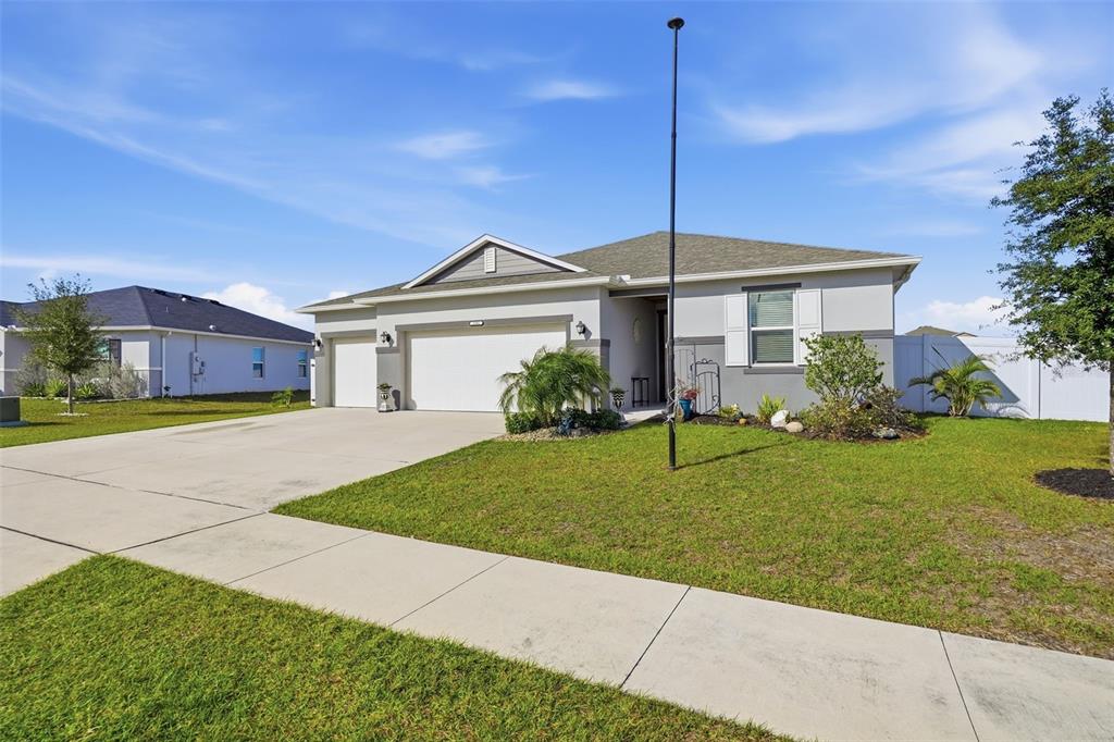 A single-story suburban house features a two-car garage, a concrete driveway, and a grassy lawn — 2201 GLADIOLUS LN LANE, MASCOTTE, FL