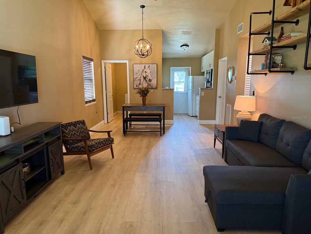 A living room features light wood-look flooring, a dark sectional sofa, and an open kitchen — 11248 PENDLETON AVENUE UNIT A&B, ENGLEWOOD, FL