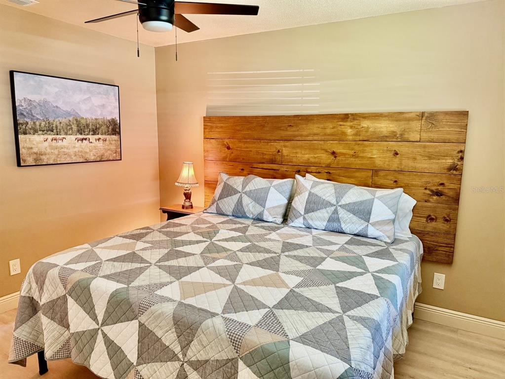 A bedroom features a wooden headboard, a geometric patterned quilt, and a ceiling fan — 11248 PENDLETON AVENUE UNIT A&B, ENGLEWOOD, FL