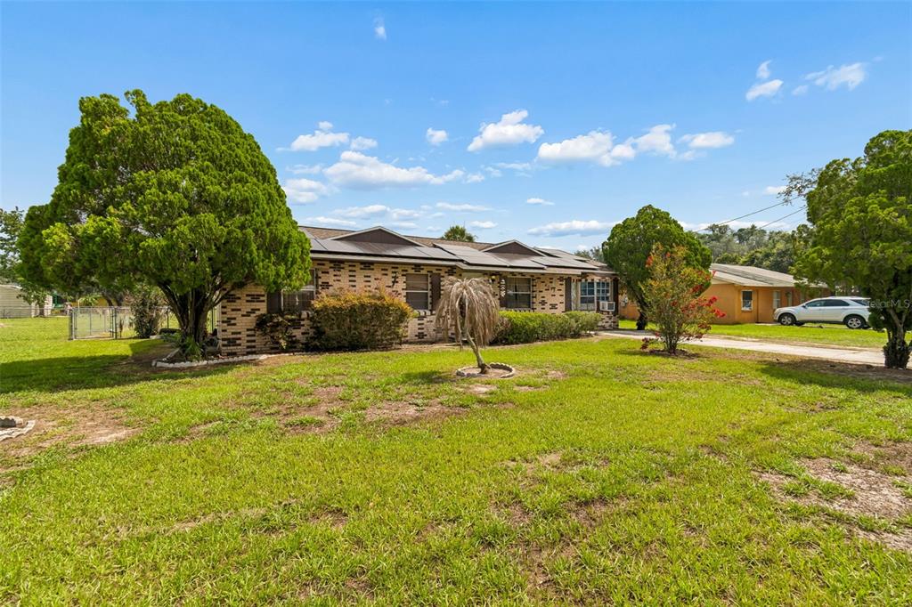 A single-story brick house with a dark roof sits on a grassy lot with trees — 4087 WILLOW SOUTH DRIVE, MULBERRY, FL