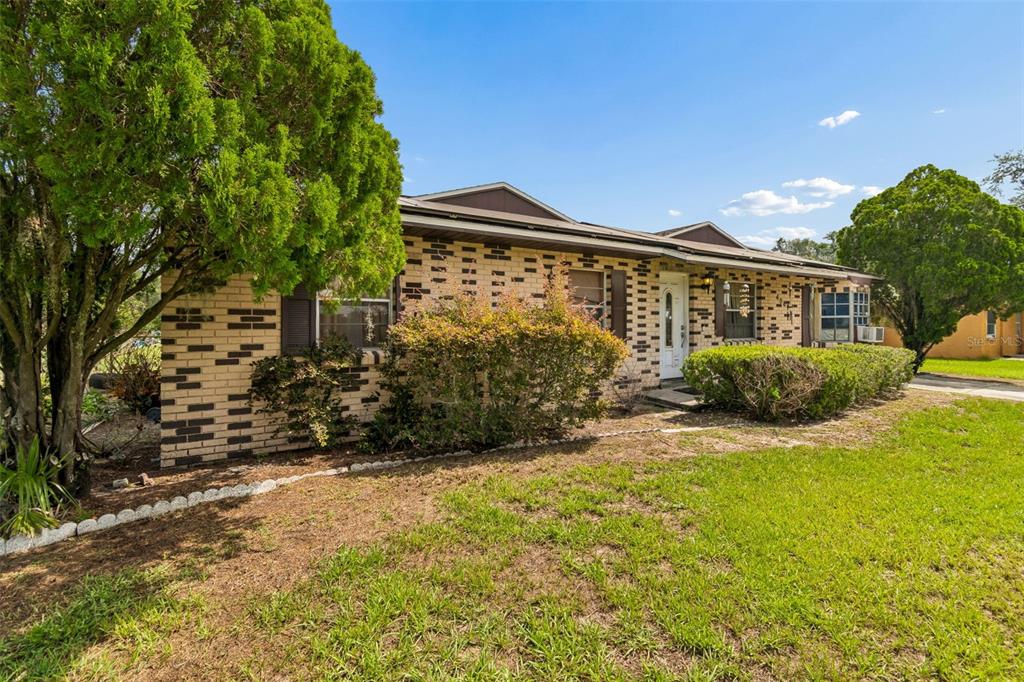 A single-story brick house with a front lawn, mature trees, and dark window shutters — 4087 WILLOW SOUTH DRIVE, MULBERRY, FL