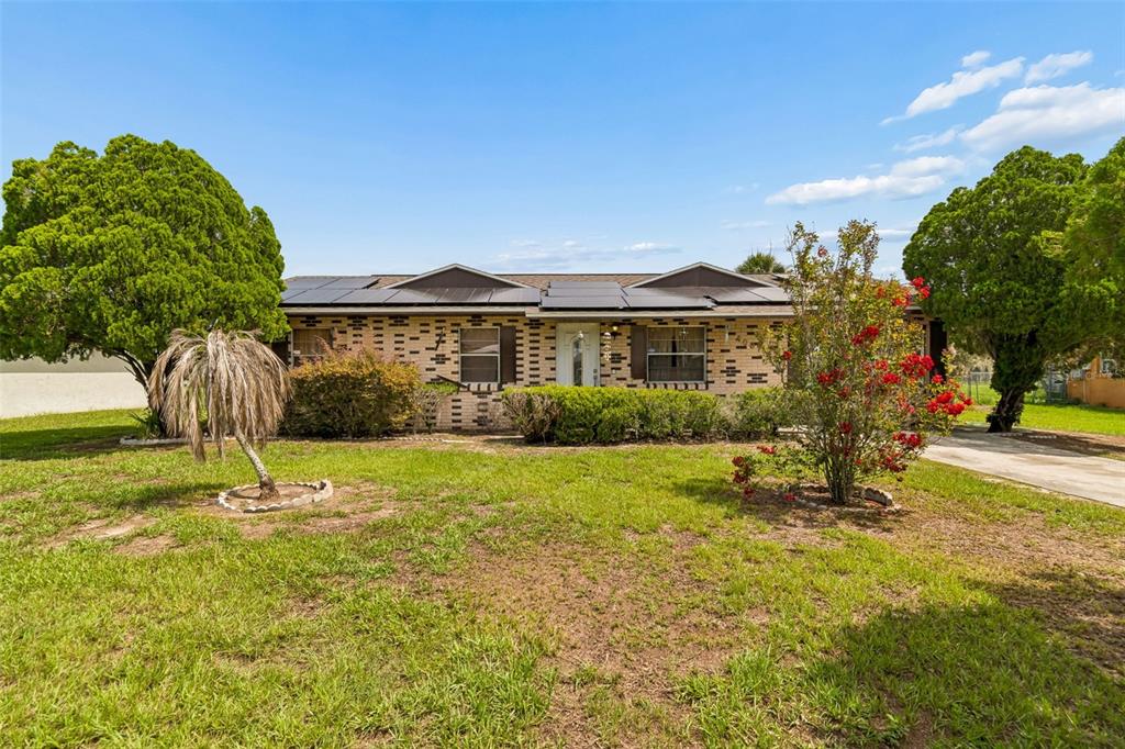 A single-story brick house with solar panels on the roof and a front lawn — 4087 WILLOW SOUTH DRIVE, MULBERRY, FL