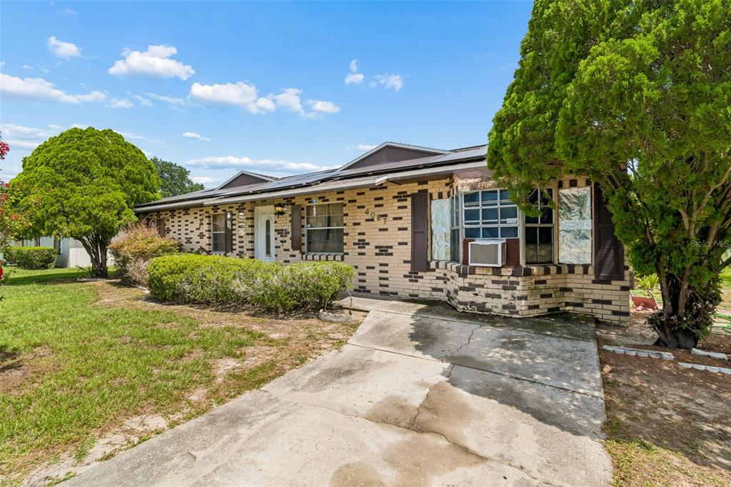 A single-story brick house with a concrete driveway, a front lawn, and mature trees — 4087 WILLOW SOUTH DRIVE, MULBERRY, FL