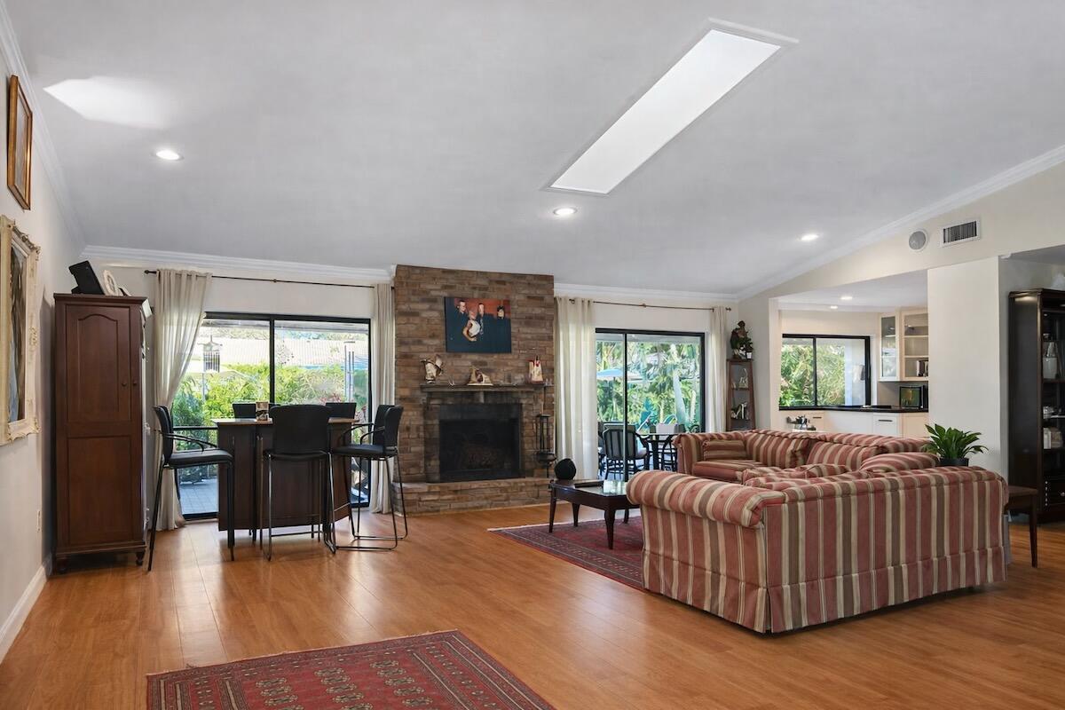 A living room with a brick fireplace, striped sofa, and sliding glass doors to a patio — 20952 Delagado Terrace, Boca Raton FL 33433, BOCA RATON, FL