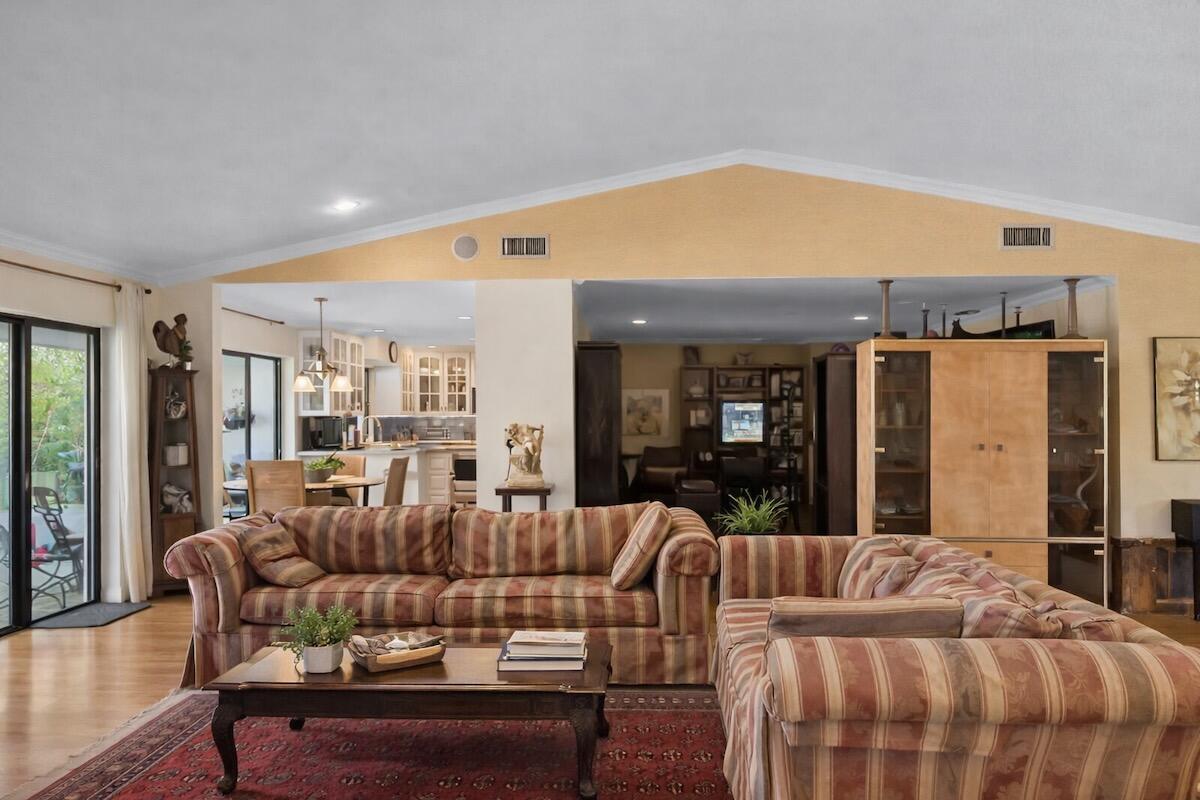 A living room with a plaid sofa, coffee table, and an open view into the kitchen — 20952 Delagado Terrace, Boca Raton FL 33433, BOCA RATON, FL