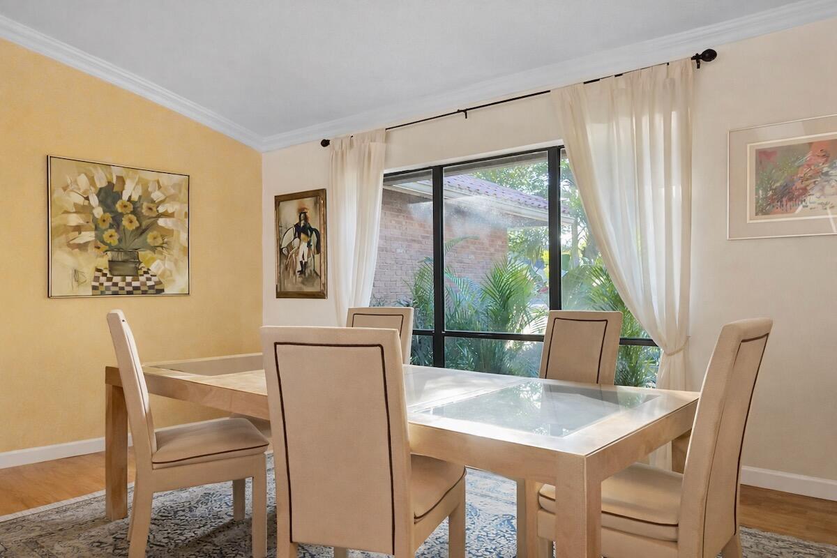 A dining room features a light-colored table, upholstered chairs, a yellow accent wall, and windows — 20952 Delagado Terrace, Boca Raton FL 33433, BOCA RATON, FL