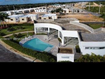 An aerial view shows a modern white building with a curved facade and a swimming pool — Alta Vista l Villa PUNTA CANA, FL, FL