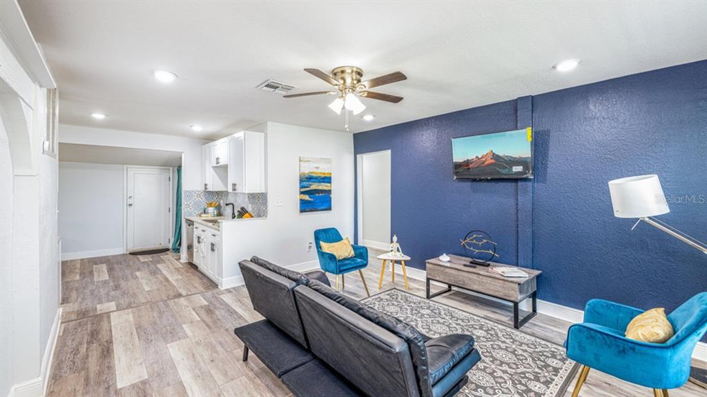A living room features a dark blue accent wall, a sofa, two blue chairs, and kitchen — 7508 CAROLYN AVENUE, ORLANDO, FL