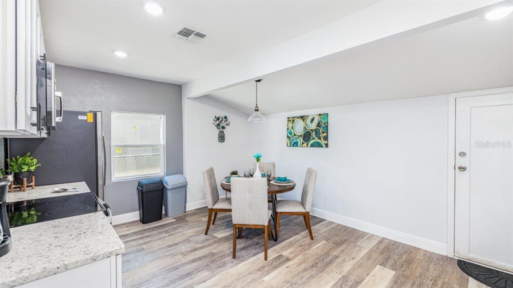 A kitchen and dining area feature white cabinets, granite countertops, and wood-look flooring — 7508 CAROLYN AVENUE, ORLANDO, FL