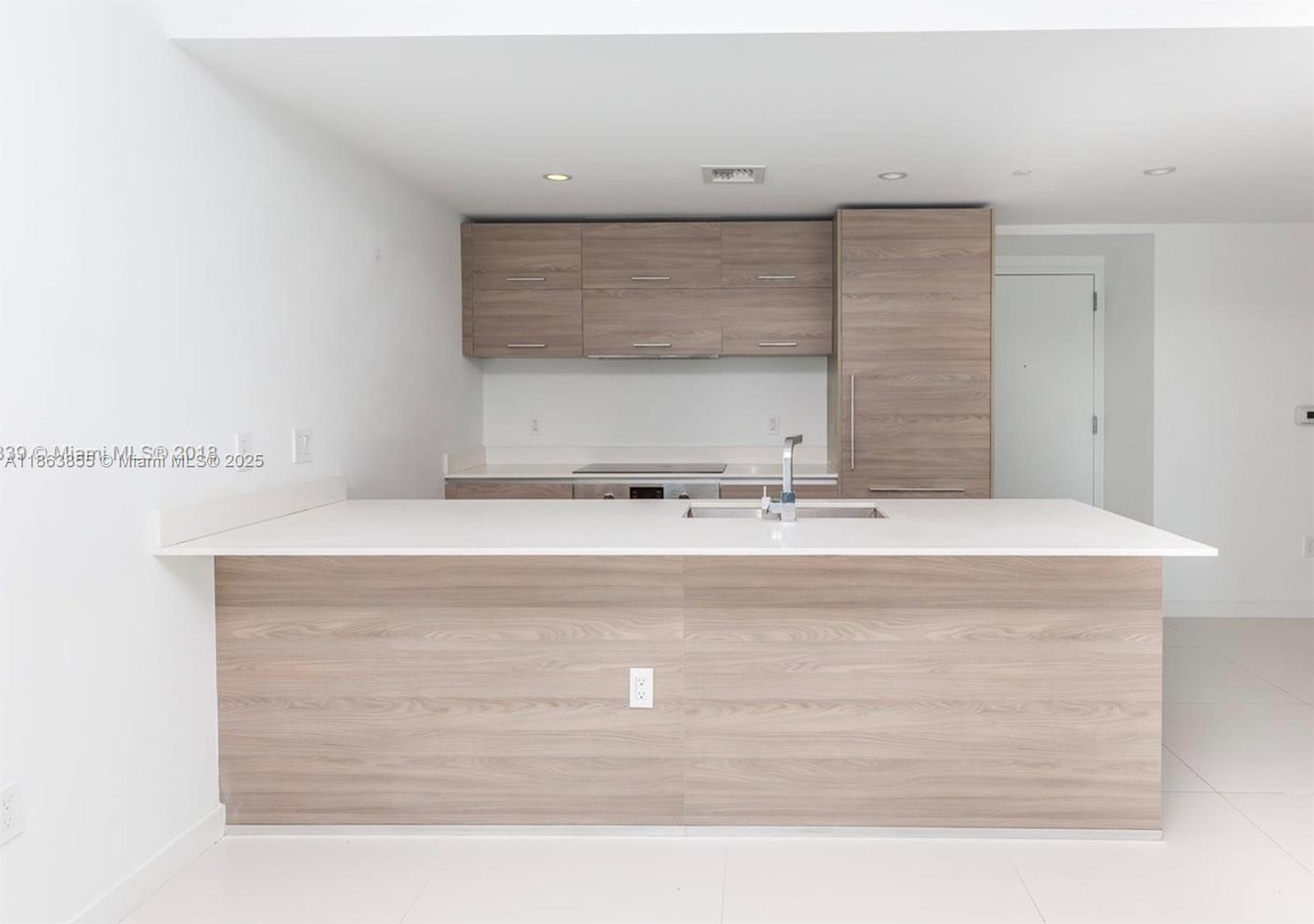 A modern kitchen features light wood cabinetry, a white countertop, and a central island — 1300 S Miami Ave # 1602, Miami FL 33130, MIAMI, FL