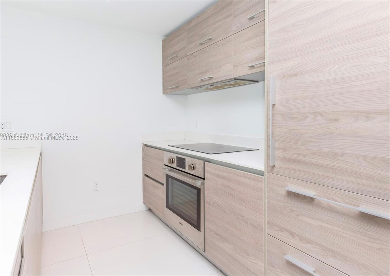 A modern kitchen features light wood-grain cabinetry, stainless steel appliances, and white countertops — 1300 S Miami Ave # 1602, Miami FL 33130, MIAMI, FL