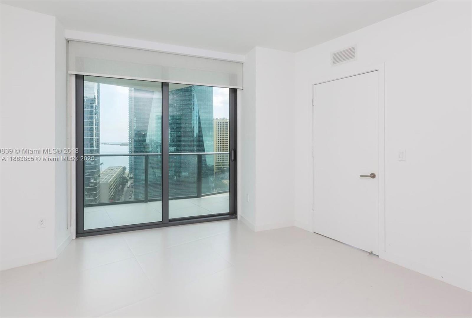 An empty room with white walls, light tile flooring, a sliding glass door, and balcony — 1300 S Miami Ave # 1602, Miami FL 33130, MIAMI, FL