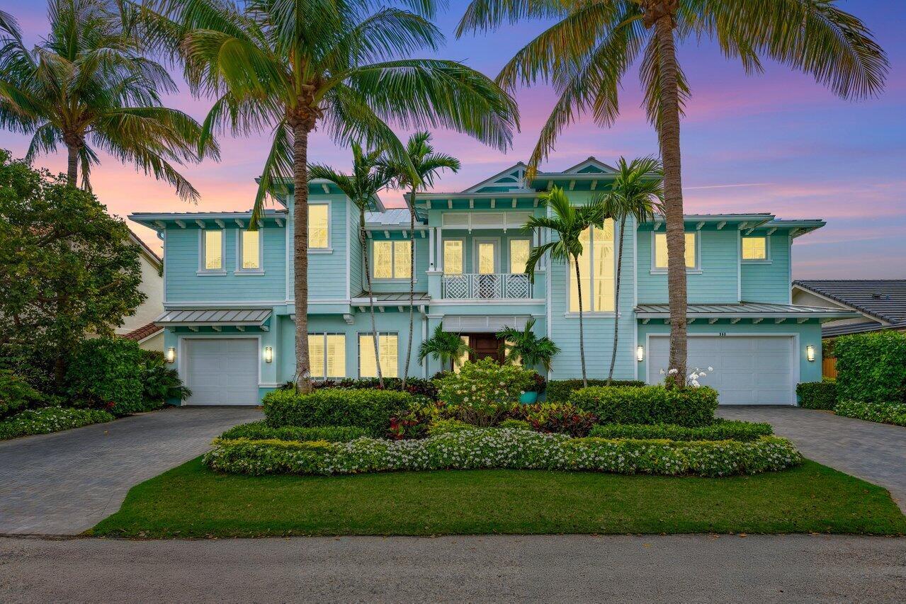 A two-story, light blue coastal-style house features a symmetrical facade, two garages, and palm trees — 960 Dogwood Drive, Delray Beach FL 33483, DELRAY BEACH, FL