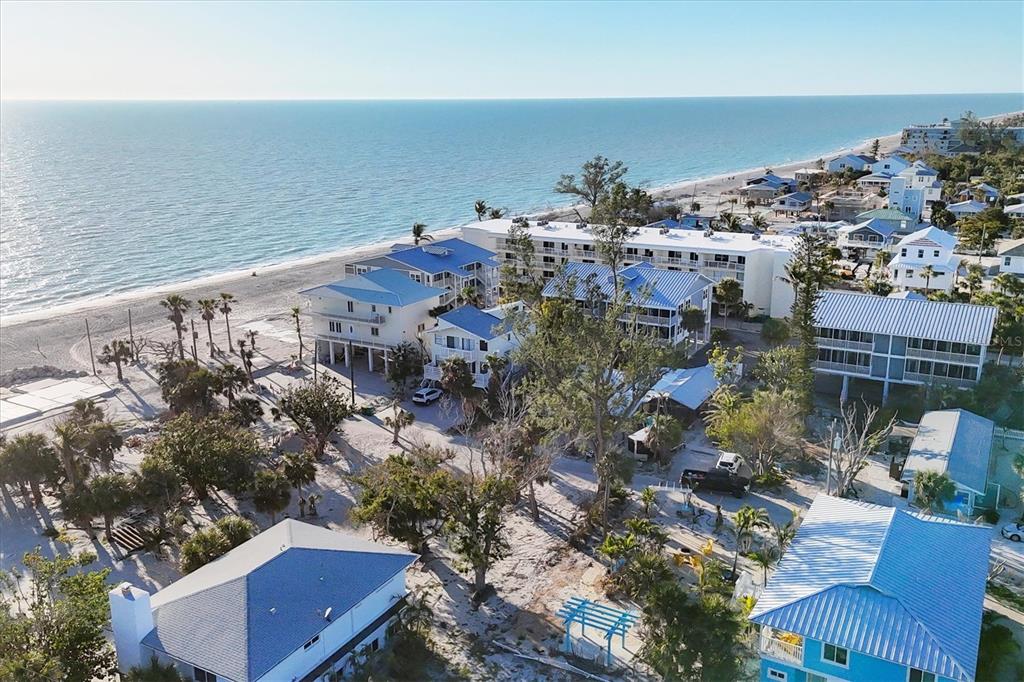 An aerial view of beach houses and a multi-story building along a sandy coastline — 65 BEACHCOMBER LANE UNIT B, ENGLEWOOD, FL