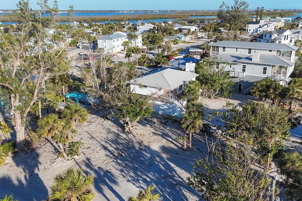 An aerial view shows a single-story house with a sandy yard and surrounding coastal neighborhood — 65 BEACHCOMBER LANE UNIT B, ENGLEWOOD, FL