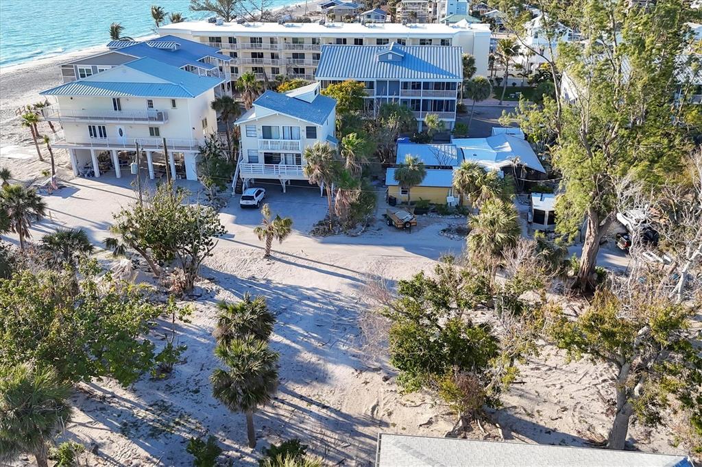 An aerial view shows several beach houses and a multi-story building near the ocean — 65 BEACHCOMBER LANE UNIT B, ENGLEWOOD, FL