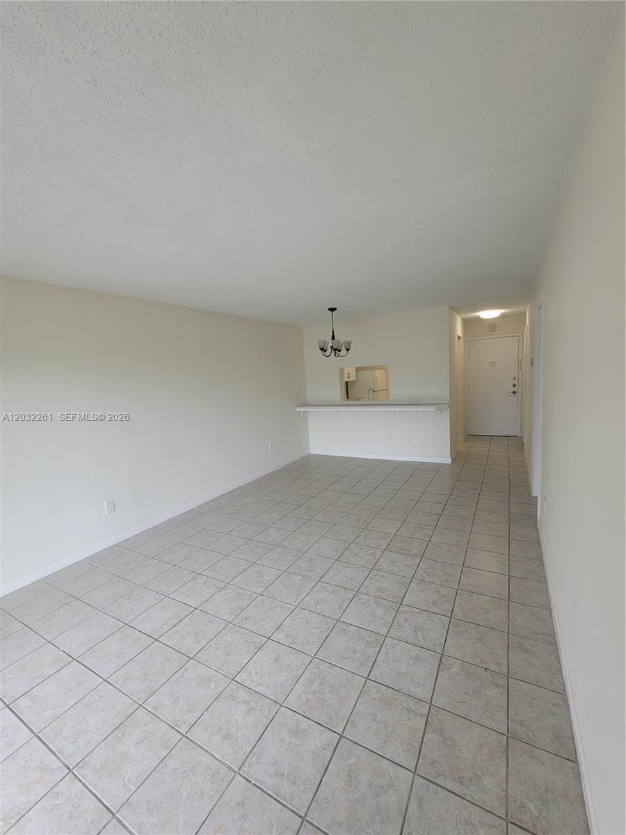 An open living area features light-colored tile flooring, a breakfast bar, and a dining chandelier — 2800 NW 56th Ave # E401, Lauderhill FL 33313, LAUDERHILL, FL