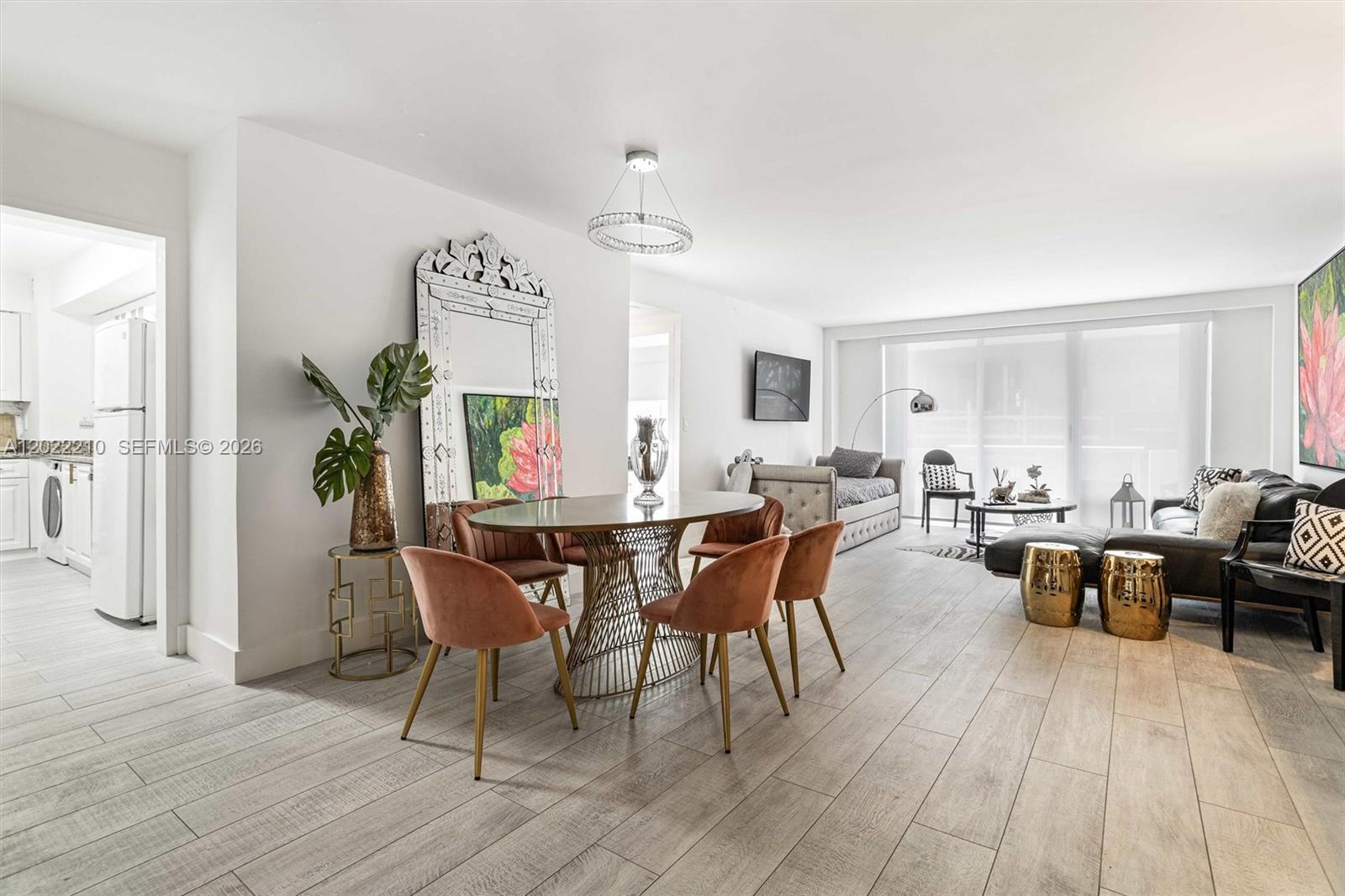 A dining area with velvet chairs and a round table sits beside a living room — 9195 NE Collins Ave # 1104, Surfside FL 33154, SURFSIDE, FL