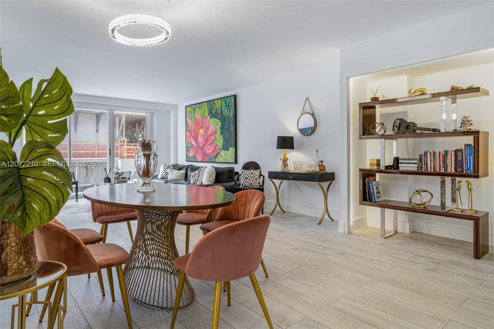 A dining area with a round table and velvet chairs sits beside a living room — 9195 NE Collins Ave # 1104, Surfside FL 33154, SURFSIDE, FL