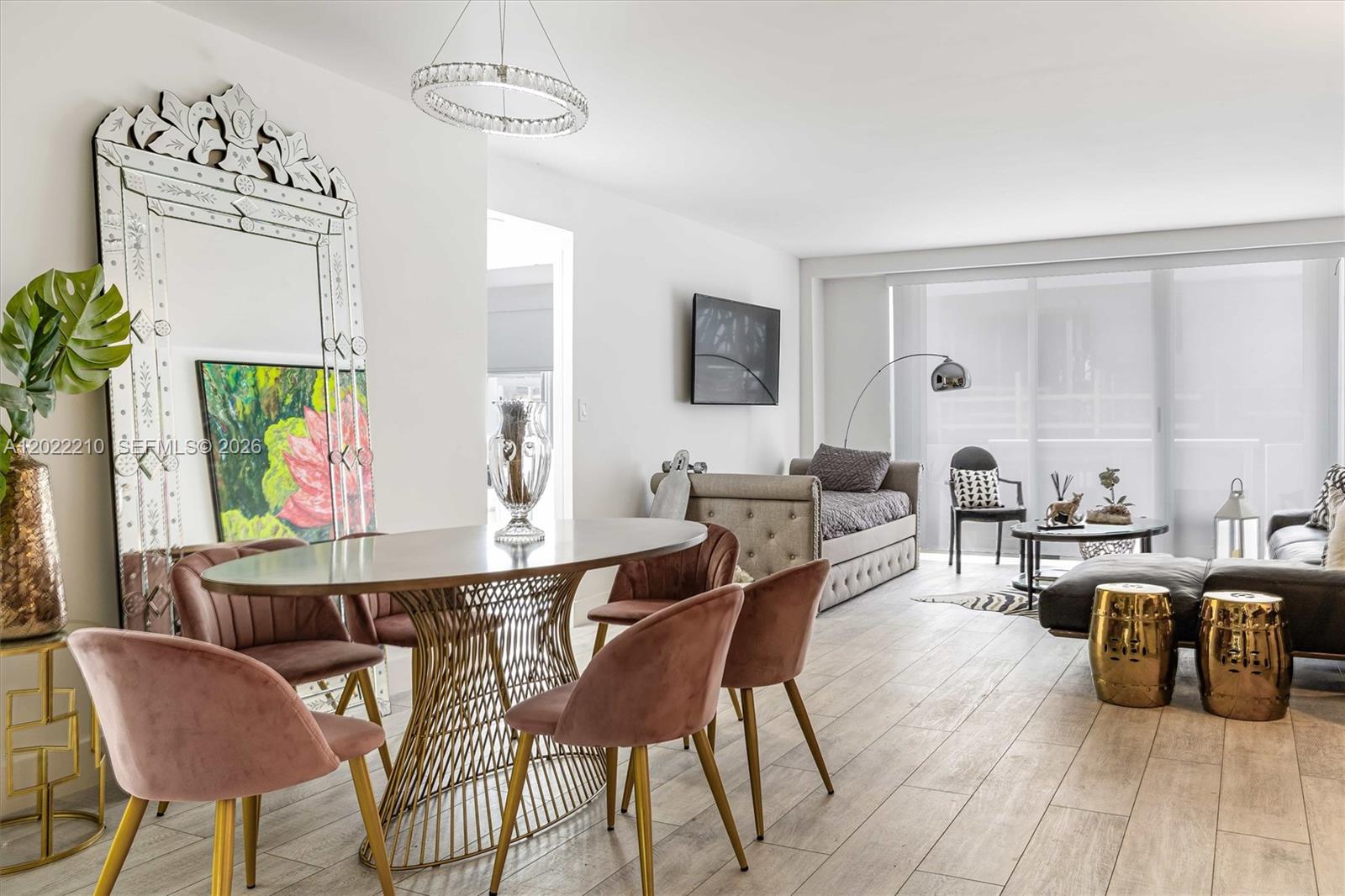 A dining area with a glass table and pink chairs sits beside a living room — 9195 NE Collins Ave # 1104, Surfside FL 33154, SURFSIDE, FL