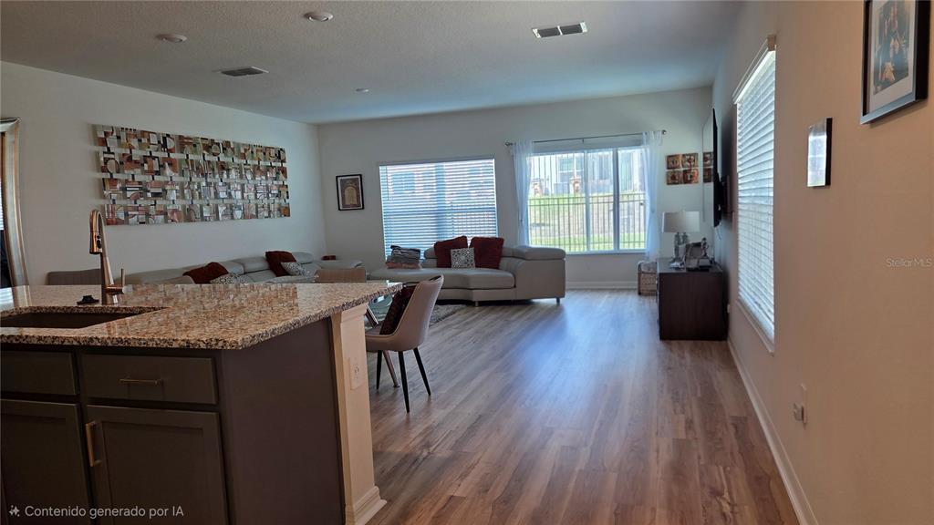 An open-concept living room features wood-look flooring, a granite-topped kitchen island, and a sectional sofa — 728 STONEY POINT CIRCLE, DAVENPORT, FL