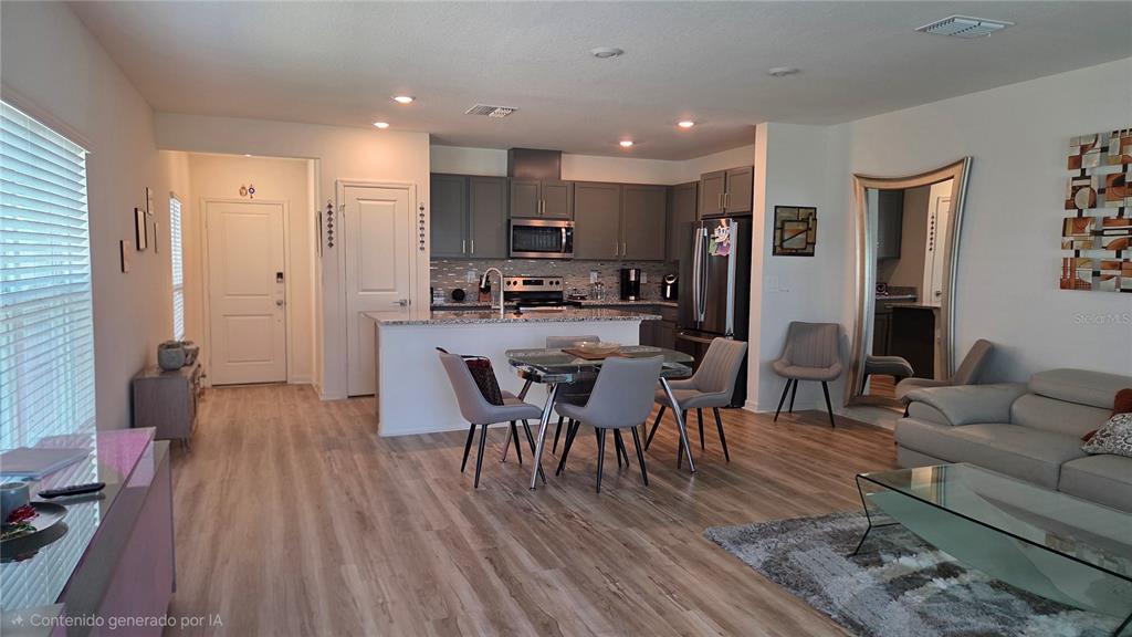An open-concept kitchen and living area featuring gray cabinetry, a dining table, and light flooring — 728 STONEY POINT CIRCLE, DAVENPORT, FL