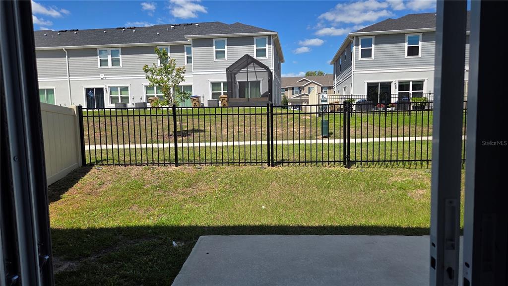A view from a doorway looking out at a small backyard with a metal fence — 728 STONEY POINT CIRCLE, DAVENPORT, FL