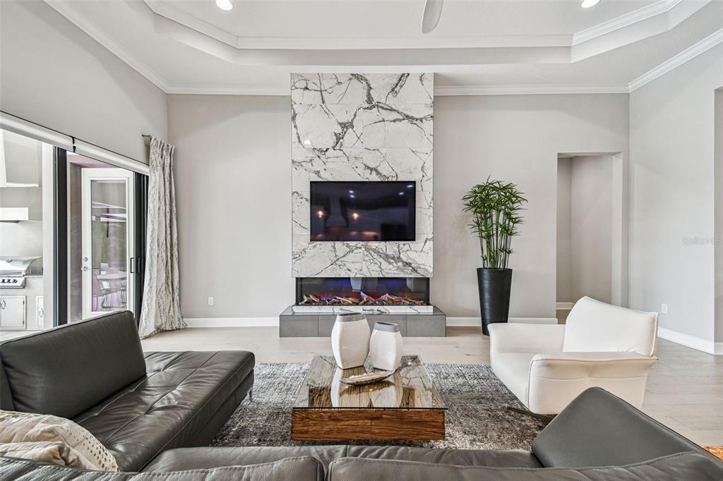 A living room features a marble-tiled fireplace wall, a television, and modern furniture — 4054 ROCKY SHORES DRIVE, TAMPA, FL