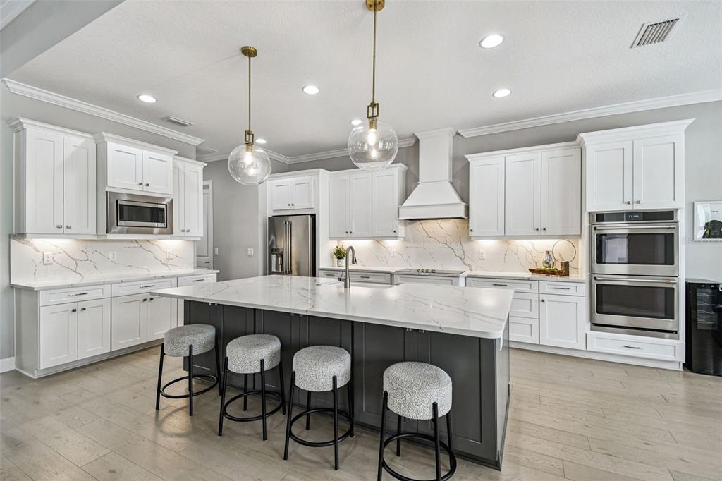 A modern kitchen features white cabinetry, a dark gray island, and marble-style countertops — 4054 ROCKY SHORES DRIVE, TAMPA, FL