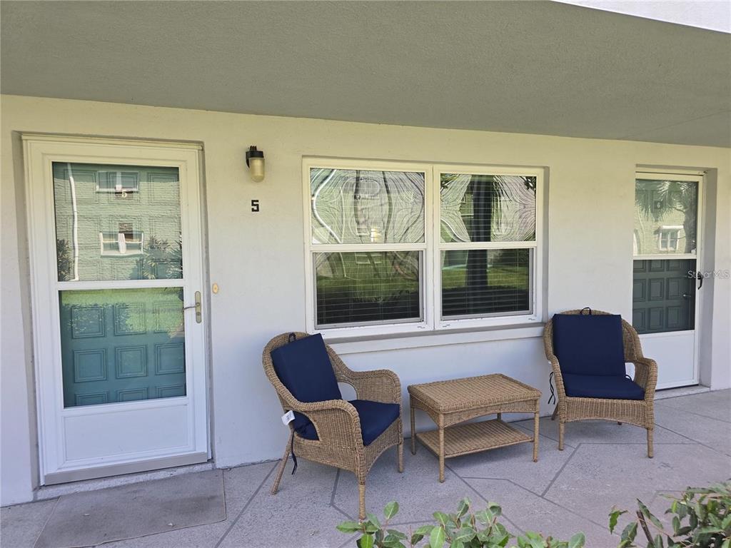 A patio features two wicker chairs with blue cushions and a matching small table — 5267 81ST STREET N UNIT 5, ST PETERSBURG, FL
