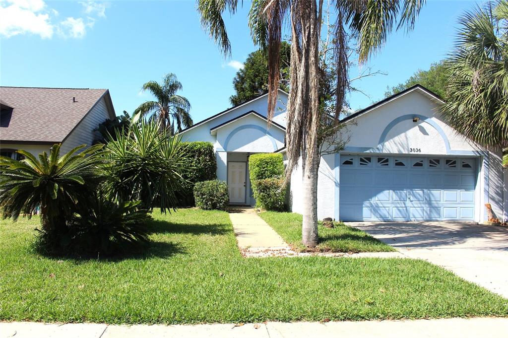 A single-story house with a light blue exterior, a front-facing garage, and palm trees — 3036 DELLCREST PLACE, LAKE MARY, FL