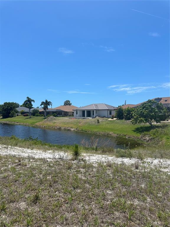 A view of a residential canal and houses from a grassy, undeveloped lot — 11 MEDALIST WAY, ROTONDA WEST, FL