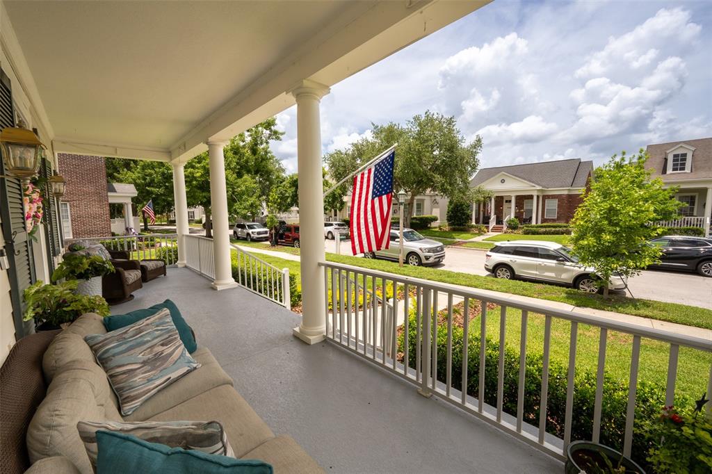 A covered front porch features a dark double door with floral wreaths and wicker furniture — 712 TEAL AVENUE, CELEBRATION, FL