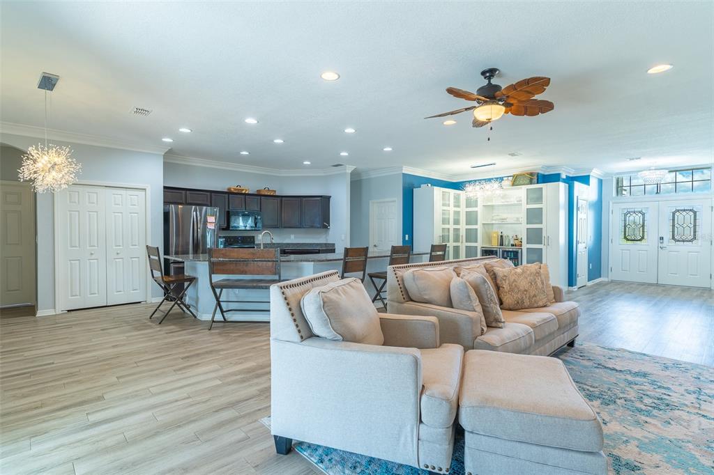 An open-concept living room and kitchen featuring light wood floors and a ceiling fan — 3749 FIELDSTONE CIRCLE, WINTER HAVEN, FL